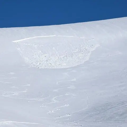SAIS Southern Cairngorms Lumps of snow at the bottom of where the avalanche happened on a mountainside covered in deep snow.