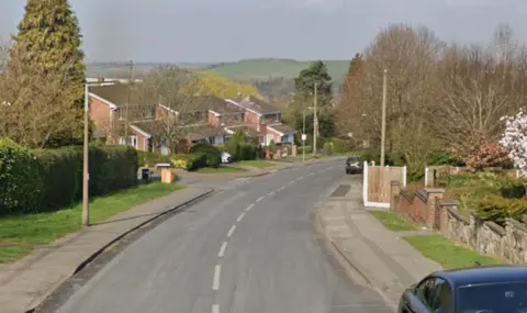 Google A street view, lined by homes and lamp-posts, with green hills in the background