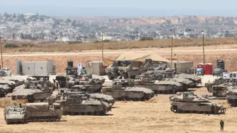 EPA Israeli tanks and other military vehicles gather at an undisclosed location in southern Israel near the Gaza border (14 May 2025)