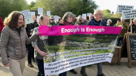 A crowd of protesters holding a banner saying "Enough is Enough"