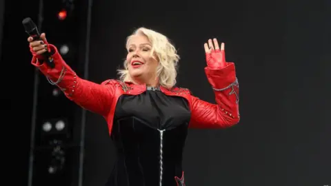 Kim Wilde performs at Radio 2's Big Weekend - she wears a red and black jacket with stars on and studs on the red sleeves