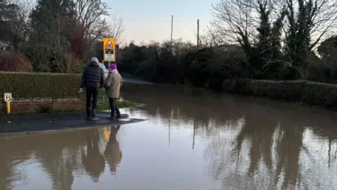 Two people stood on a small stretch of pavement surrounded by water