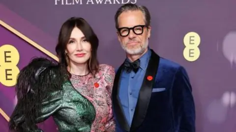 Getty Images Carice van Houten and Guy Pearce; she is in a green and pink dress and he is in a blue, velvet suit