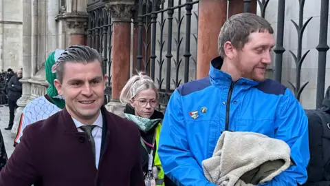 Lawyer Darragh Mackin arrives with DJ Provai and Dan Lambert - Kneecaps band manager 