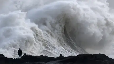 Reuters Silhouette of person viewing large waves as Storm Eowyn arrives, in Porthcawl, Wales, Britain, January 24, 2025. 