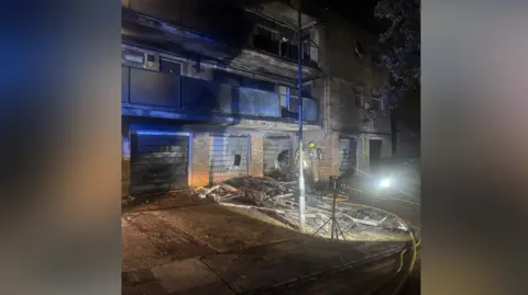 LFB A block of flats severely damaged by fire. Firefighters an be seen assessing the damage. The fire is out. 