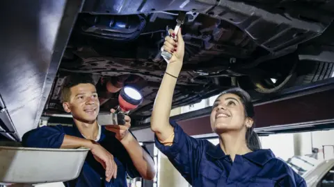 Getty Images Two student mechanics repairing a car