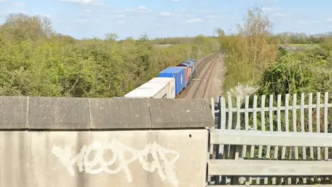 Google A view of a freight train from a bridge over the rail track 