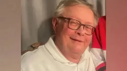 Family photograph Stuart Everett in a white polo shirt and black rimmed glasses - smiling. he has grey hair. 