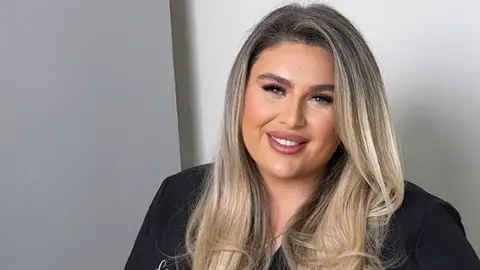 Charlotte Bates Charlotte Bates who has long blonde hair and is wearing a black beautician top 