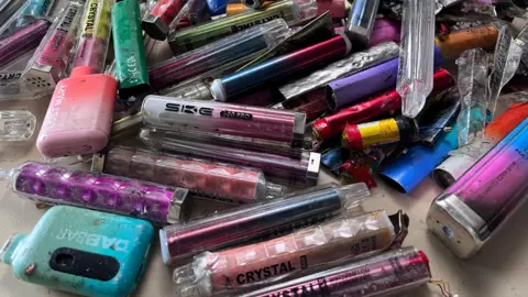 Vapes in all shapes and sizes and colours in a pile