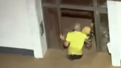 Man holding a small child in flood water