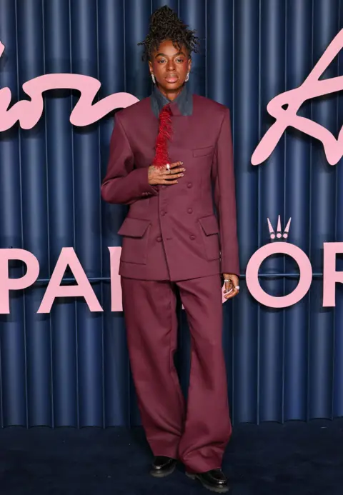 Getty Images Cat Burns looks off to the side, wearing a purple suit fringed with red feathers