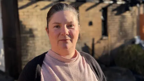 Head and shoulders image of Kirsty Knight. Kirsty has brunette hair tied back, a pink top and dark cardigan.