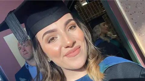 Sophie Morgan Sophie Morgan wears a black university cap and gown and smiles at the camera. She has brown short hair and brown eyes. 