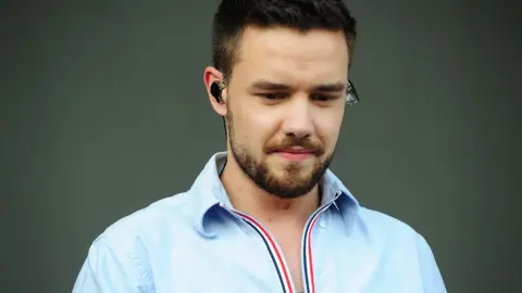 Liam Payne, wearing ear-pieces and a blue jacket onstage in Chicago, in 2018