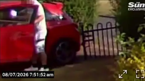 A man getting into a red car with a long object in his pocket