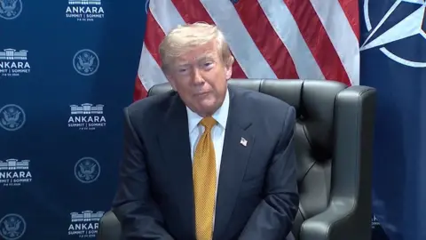 Trump in a suit and tellow tie.