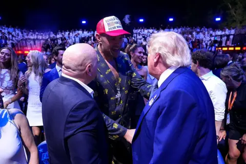 Getty Images Tyson Fury, wearing a baseball cap that reads "Donald Trump for prime minister" greets Trump himself