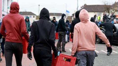 Youths carrying crates of petrol bombs in the Creggan area of Derry following an illegal dissident republican parade 