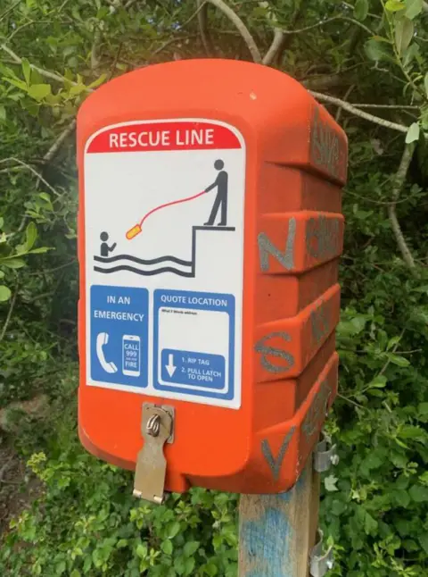 Torridge District Council A vandalised rescue line. It is bright orange and there is graffiti on the side of it.