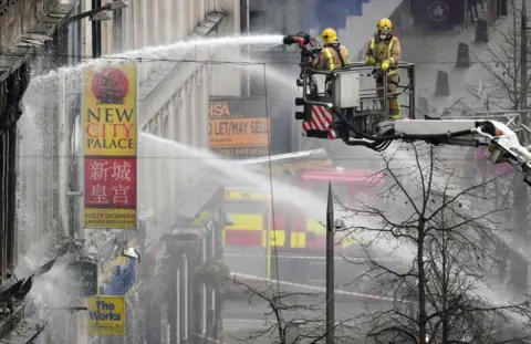 Getty Images Firefighters aiming water cannons at a building on Sauchiehall Street from a height