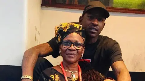 Skepta sits behing his mum Ify Adenuga