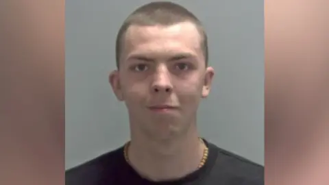 Elvis Price is wearing a black T-shirt with a shaved head and is looking directly at the camera. 