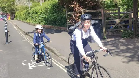 Mum cycling on bike with daughter behind