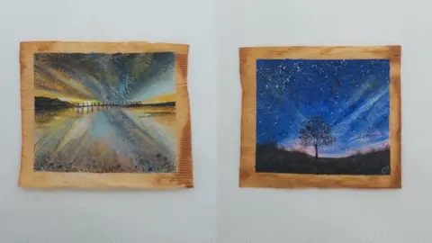 PA Media Two teabags - one with a paintings of Salturn Pier in pastel colours and the other with an image of a lone tree at nightfall on Yorkshire Dales, with stars on a navy sky