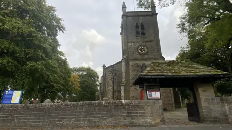 Exterior of Immanuel Church and churchyard, Oswaldtwistle with large treeds either side of it.