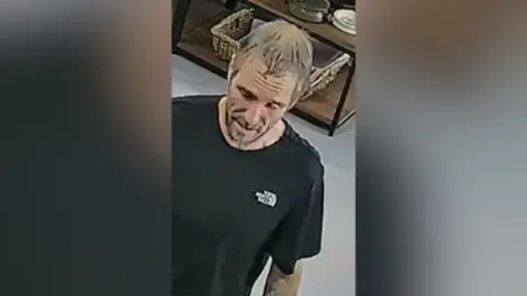 Dorset Police A CCTV image of a man wearing a black tshirt