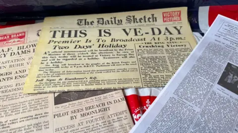 A collection of newspapers and items from VE day.