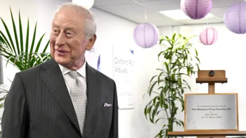 King Charles III laughs after he unveiled a plaque which accidentally fell to the floor during a visit to Oxford Photovoltaics Limited (Oxford PV), a trailblazing Oxfordshire enterprise developing advanced solar panels capable of converting more of the sun's spectrum into clean, affordable energy.