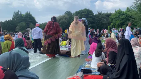 Shariqua Ahmed / BBC Muslim women dressed in their abayas and head scarfs sitting in preparation for eid prayers in the park.