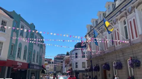 St Helier's high street with flags above the road and a sign saying Costa and Bella Italia