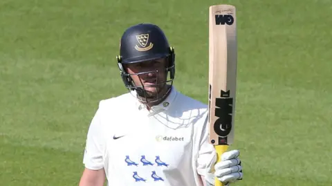 Ollie Robinson raises his bat after scoring a half-century for Sussex