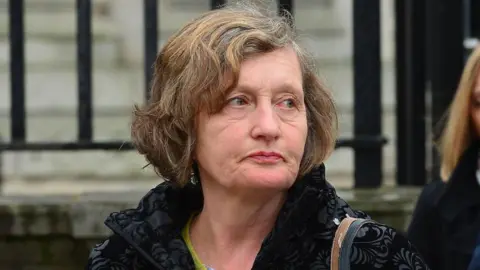 Pacemaker Geraldine Finucane, with short brown hair. She is looking to the right of the image. She is wearing a black coat. 