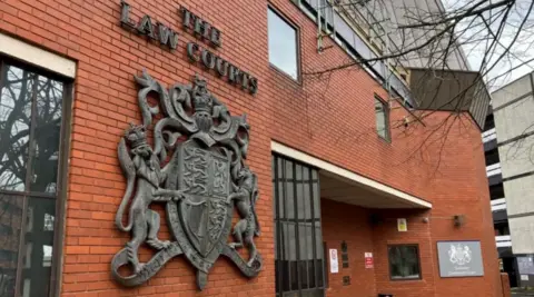 Red brick building which says 'The Law Courts' and has a large emblem below it.