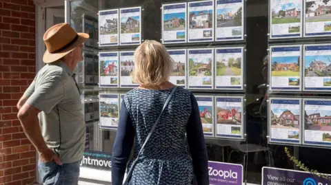 Getty Images A couple looking at property details in the window of an estate agent