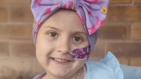 Family photo Lacie with a tube up her nose and wearing a hair wrap following chemotherapy