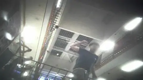 A still from Panorama's documentary. A man is seen in a grainy image with his hand held above his head, appearing to be preparing to strike something - possibly a person. 