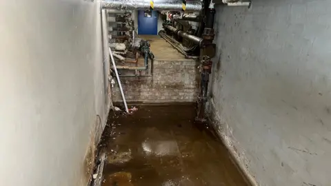 A wet concrete floor caused by leaking pipes above.