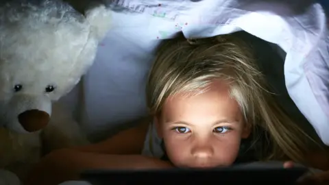 Getty Images Girl in bed with device