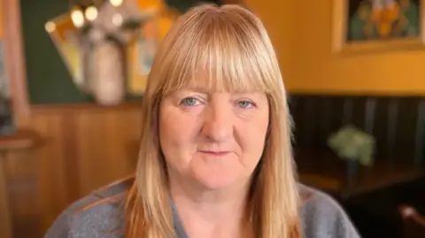 Joan has long, straight hair and blue eyes
