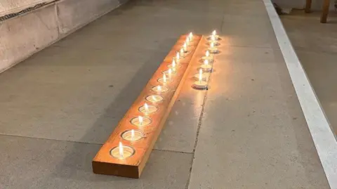 A row of lit tealight candles in a row on a step.