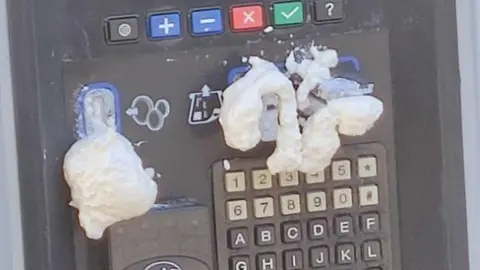 Foam can be seen on a parking machine having been sprayed into the cash and card payment slots 