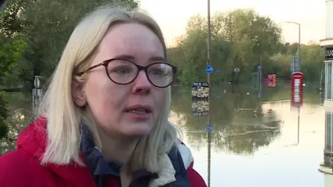 BBC Catcliffe resident Sophie Skidmore with tears in her eye and flood water in the backdrop