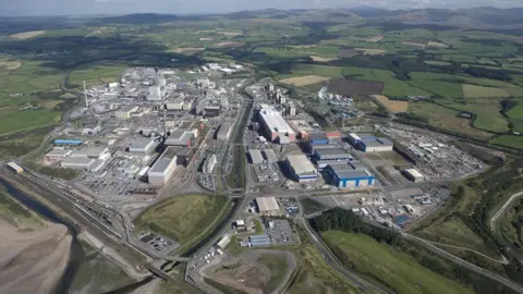 An aerial view of the Sellafield site. It is a large industrial-looking estate with several buildings and roads, surrounded by fields.