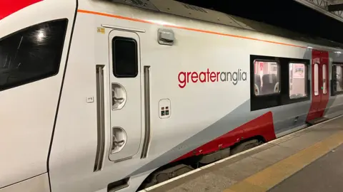 A white and red Greater Anglia train parked on the platform.